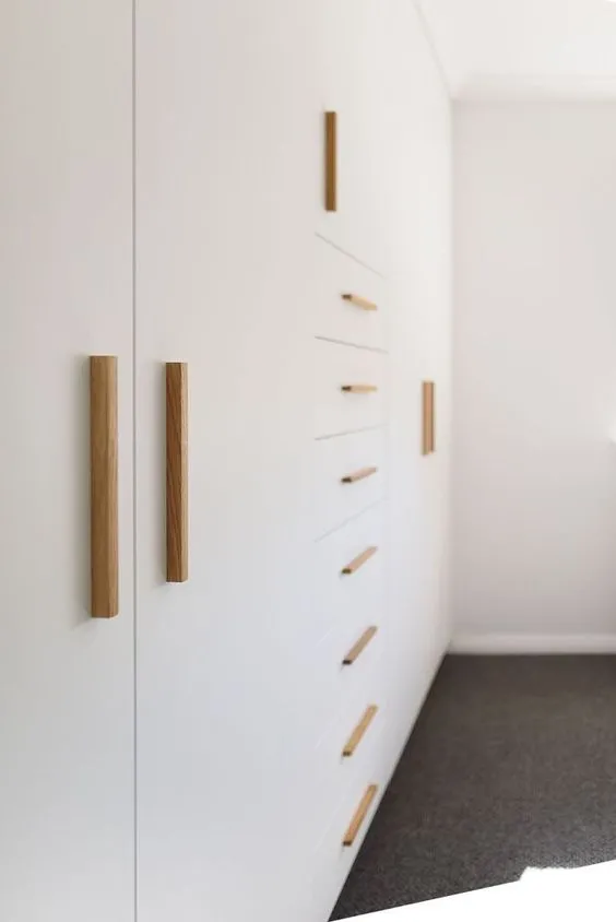 golden cylindrical handles in vertical and horizontal arrangements on a white cupboard
