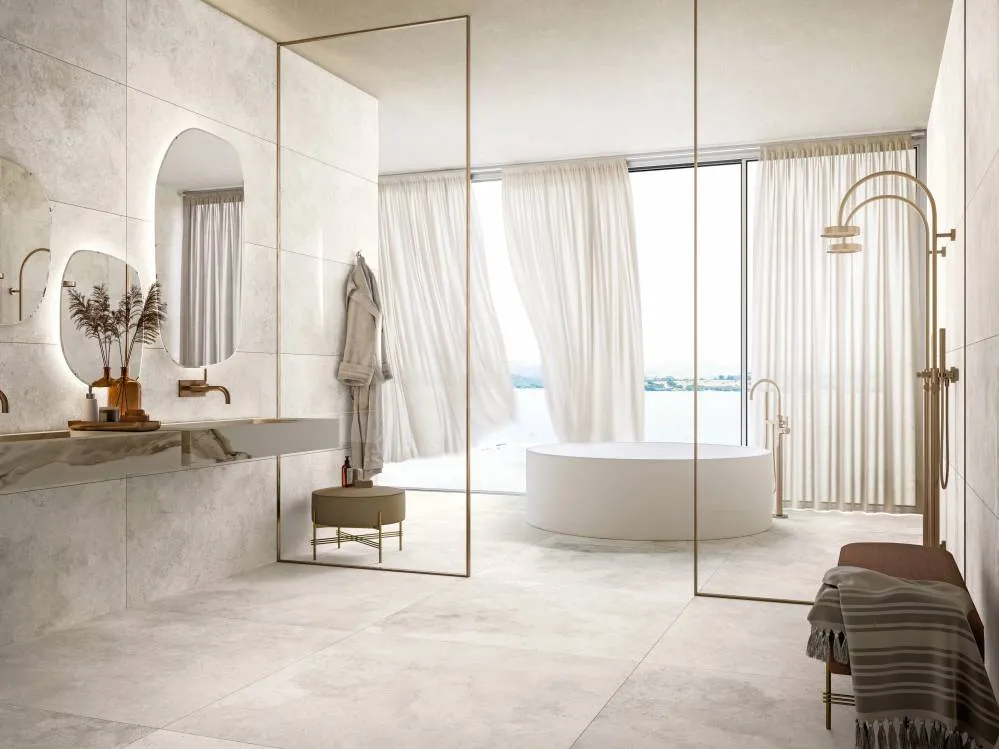 beige bath ،e with white bathtub, washbasin, mirror with light and a s،wer