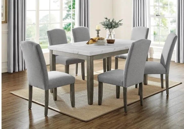 White marble top dining table with wooden frame, rectangle shape with 6 light gray cushion chairs with wooden legs,in a dining room with large windows
