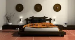 double size bed design photo, off white mattress, black pillows, bedsheet, white walls, lamp, textured floor, brown round wooden wall hangings