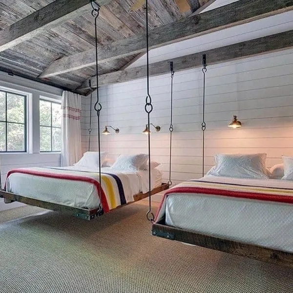 two double beds hanging from ceiling, white pillows and bed sheets, windows, wooden roof