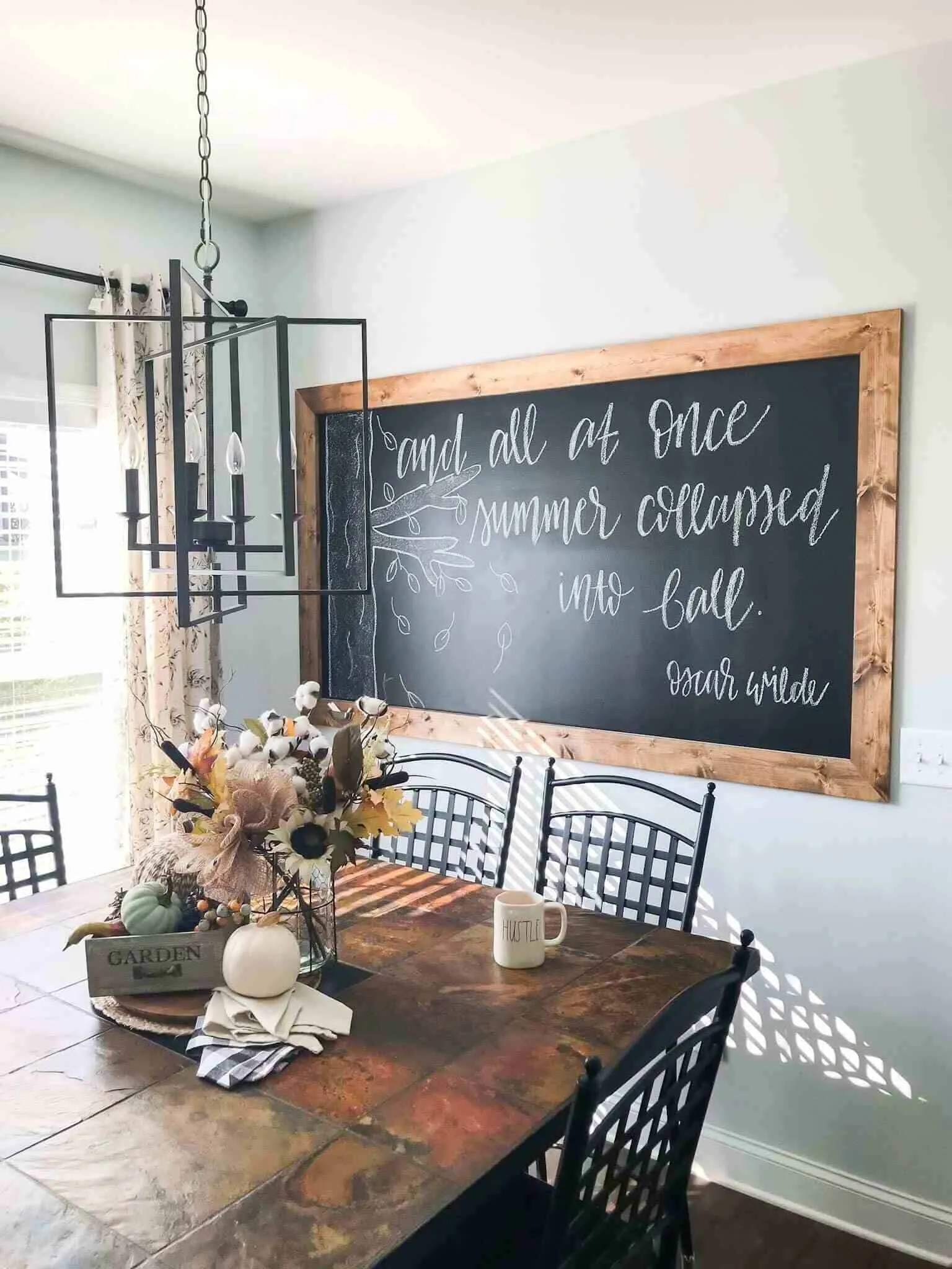 black chalkboard with brown table, chair and hanging lamp