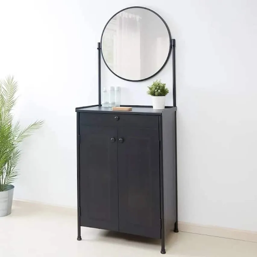 A simple black dresser with a round mirror and good storage space, in a white room.