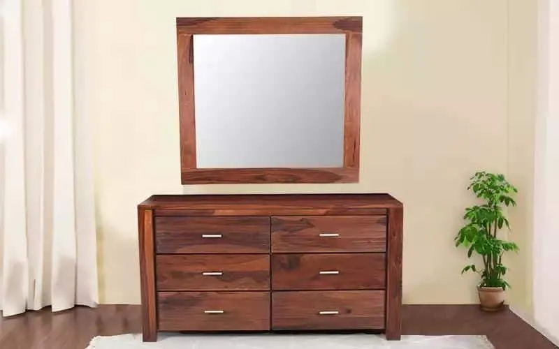A sturdy wooden dressing table design with a big square mirror and lots of storage space, in a white room.