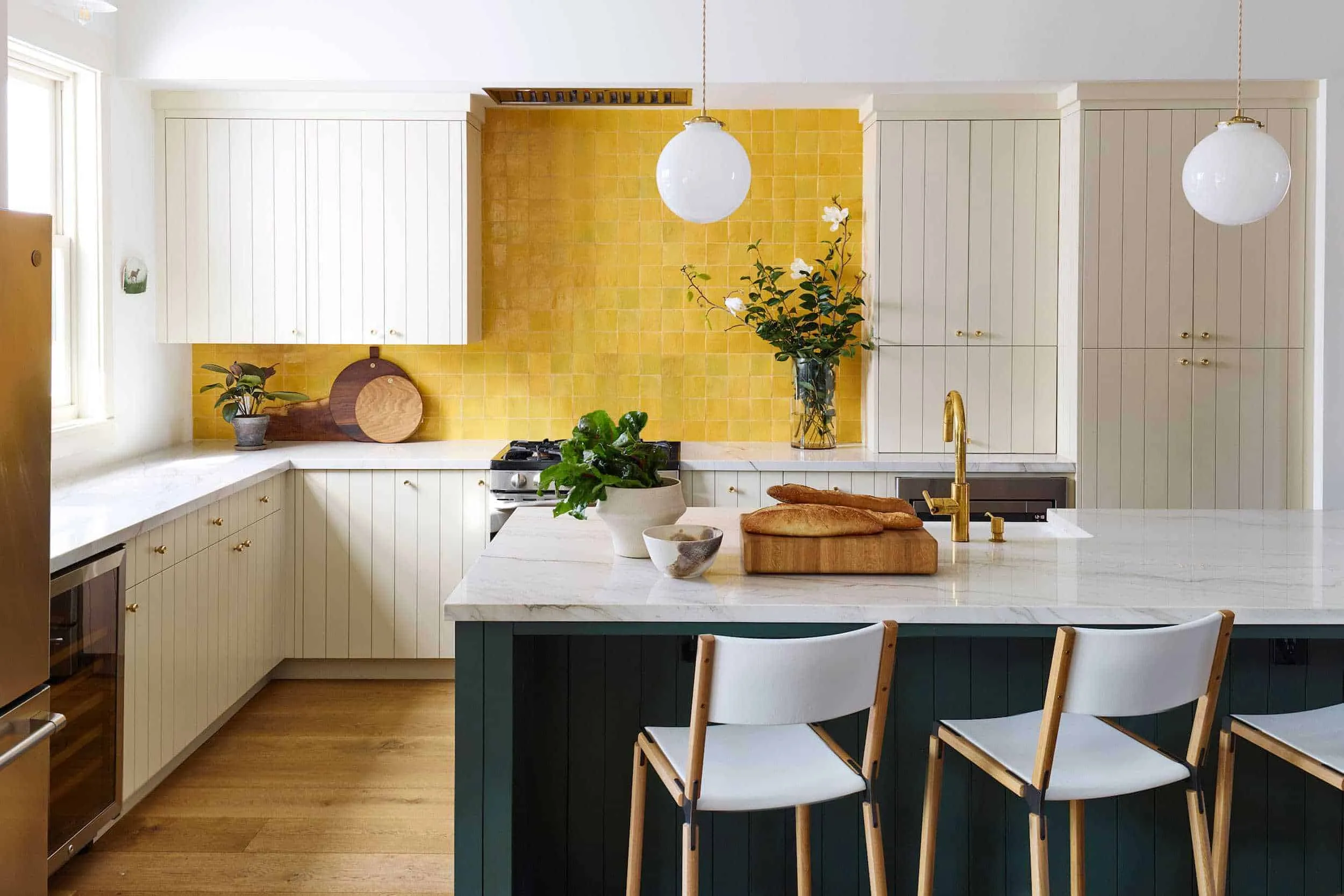 Yellow walls on kitchen with white cabinets and marble dining table top