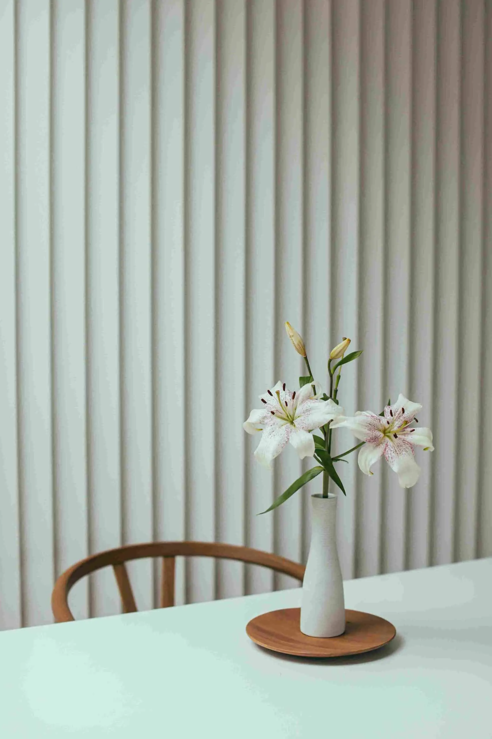 white lily flowers with a white vase a chair and table
