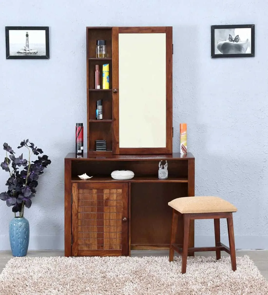 A beautiful wooden vanity with a rectangular mirror, good storage space, and a matching stool, in a blue-colored room.