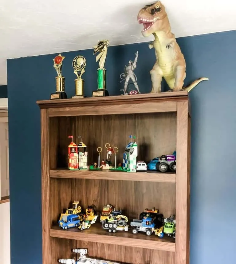 Lego mini-figures displayed in a wooden shelf on a blue wall