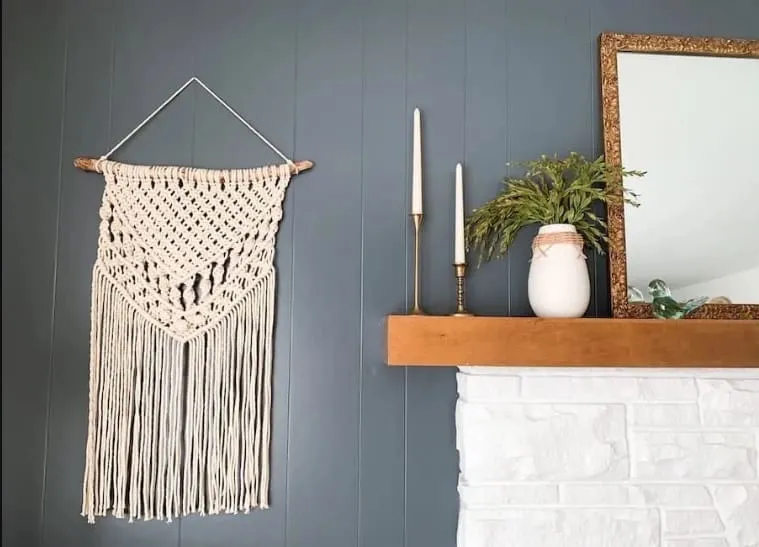 macrame art wall decoration DIY on blue wall near mantle with candlestands
