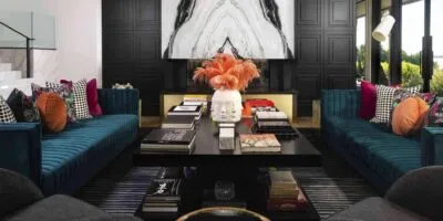 modern home decor idea for a dark themed living room with black accent wall, blue sofa, black centre table, colourful throw cushions