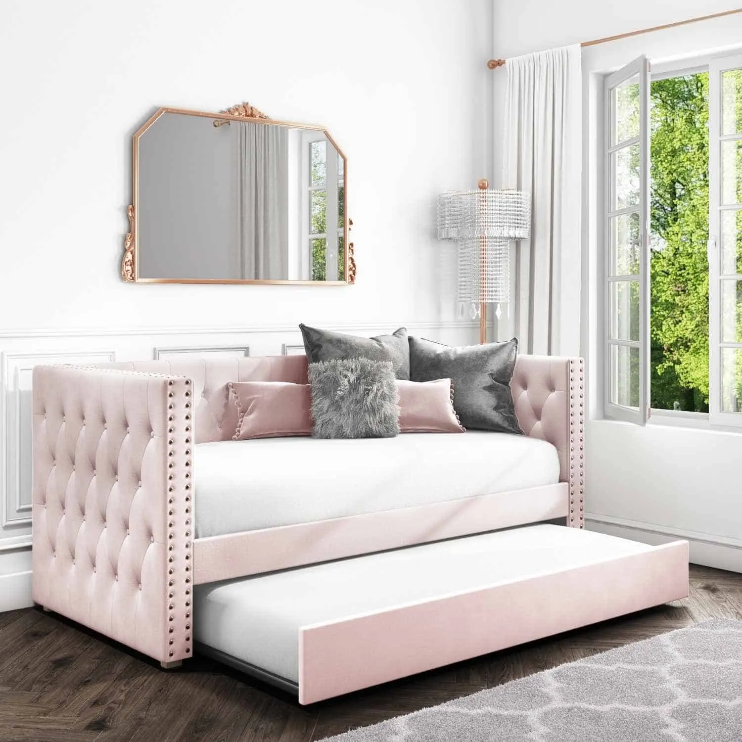pink trundle bed with cushions and a mirror