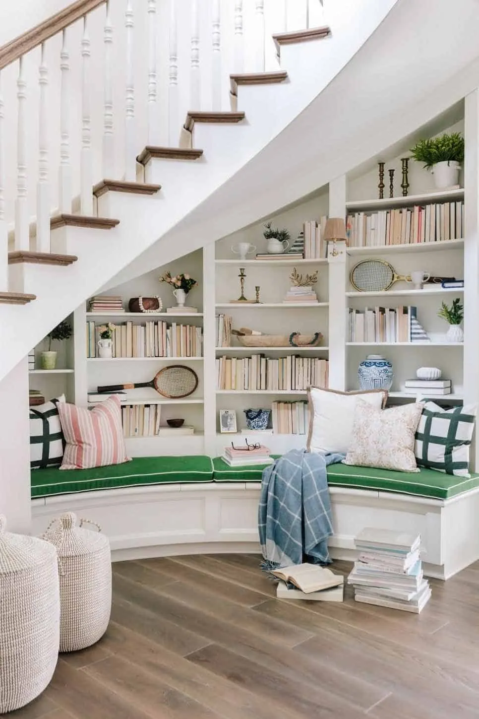 white bookshelf under stairs with books