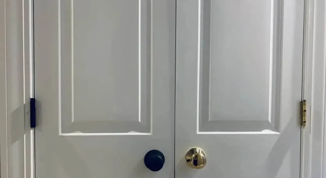 Blue door knob and hinge and gold door knob and hinge on white door