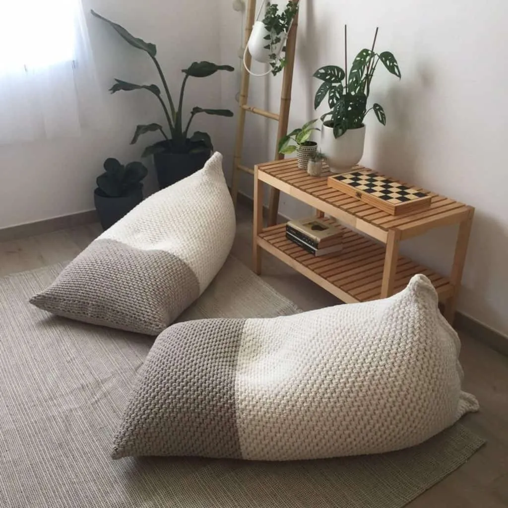 grey and white rectangle bean bag chairs with a wooden console table and some plants