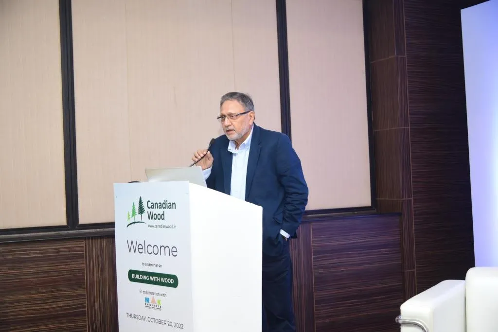 Pranesh Chhibber at the Dias in an educational Seminar on building with wood placed on a white table including engineered wood used to build sustainable villa using wood frame construction