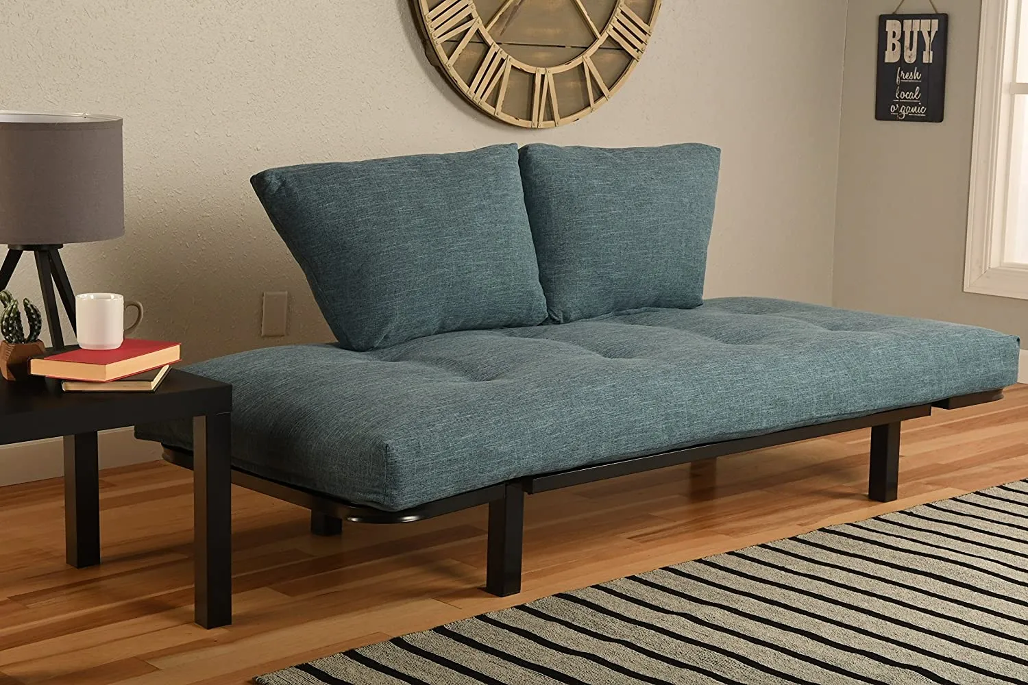 minimal living room decor, carpet, blue couch, metal furniture, wall art, table lamp beside the couch
