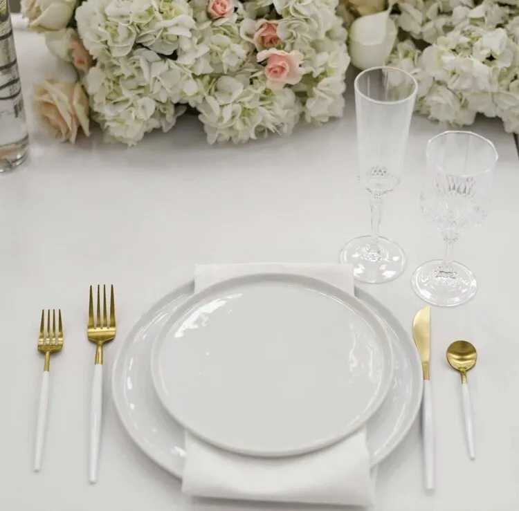 white dining table with tablecloth, floral decorations, Cutlery, plates, napkins and glasses elegant dining table setting decor ideas