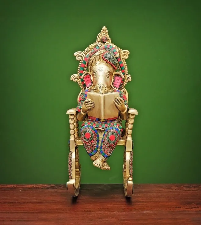 multicoloured ganpati statue seating on a rocking chair, placed on a table for home decor, metal statue