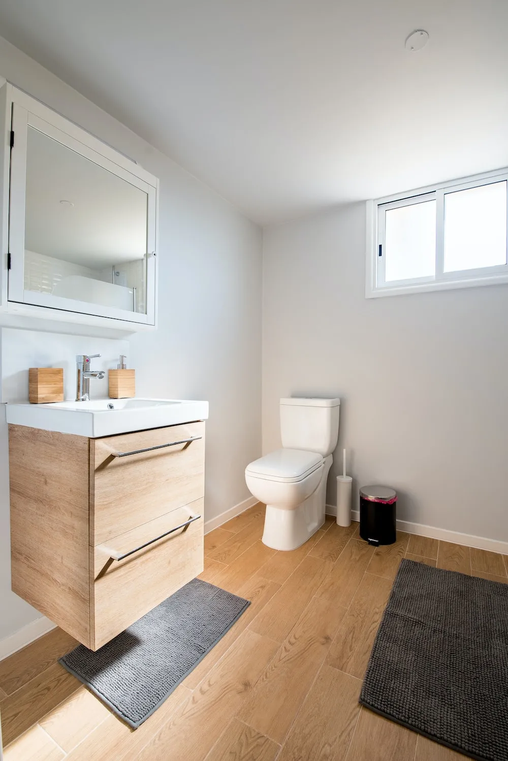 wood patterned floor for bathroom, toilet, wall-mounted vanity, mirror, rugs, lights
