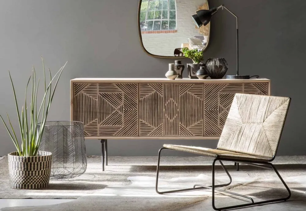 wooden sideboard with carving in a minimalist living room with an indoor plant and rattan chair