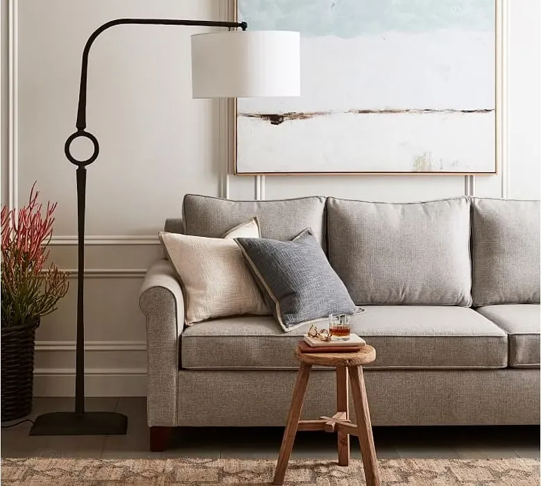 Floor lamp with an industrial meet vintage appeal placed in living room, wooden stool, grey coloured sofa