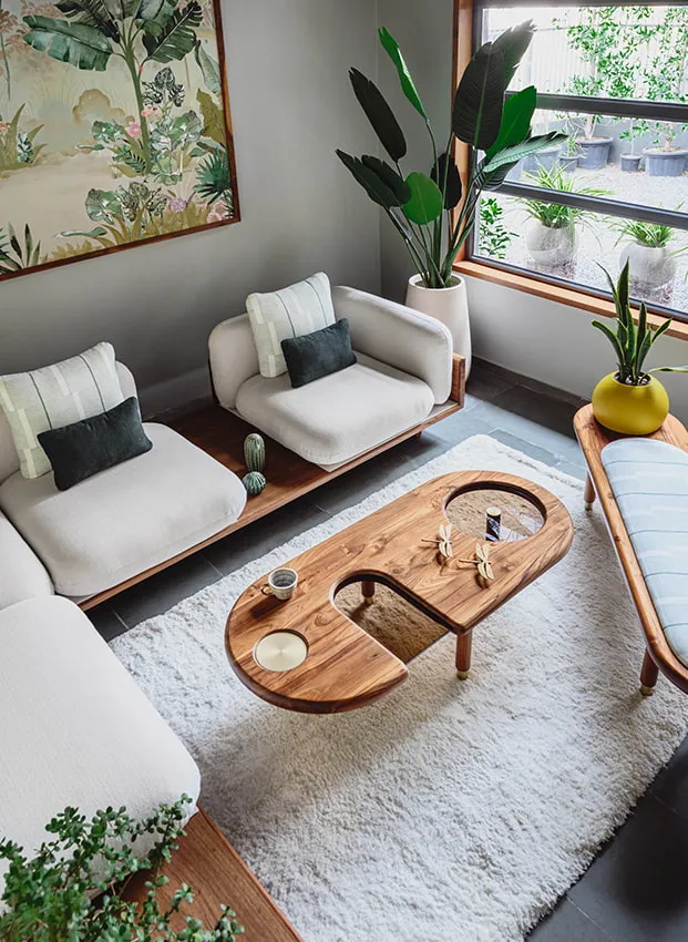 naive couch with beige coloured adds beauty to your ،me corners, wooden coffee table in the centre, indoor plants, painting hanging on the wall, beautiful living room minimal decor 