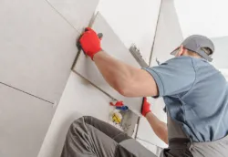 A man tiling the wall of a bathroom.
