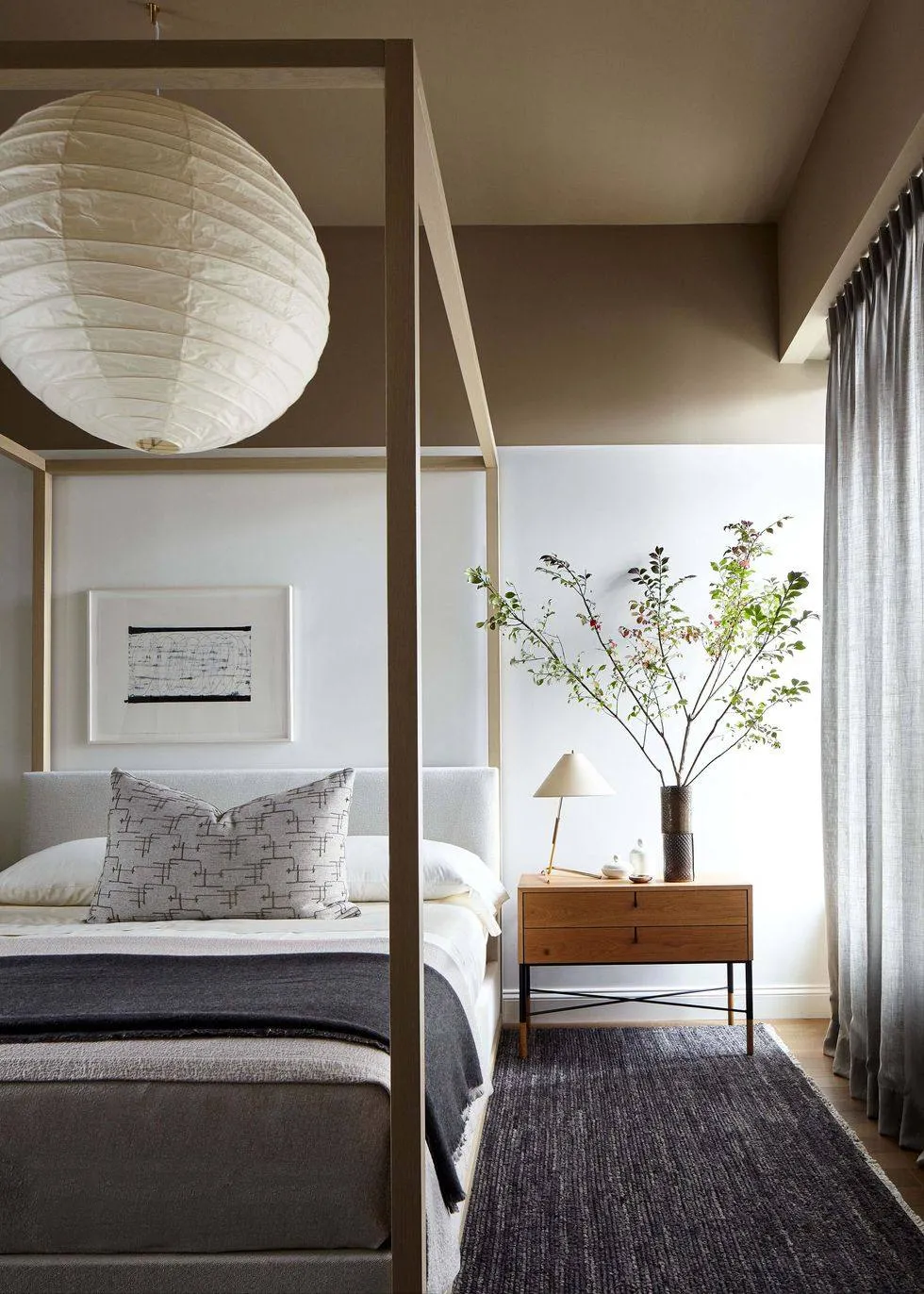 blue carpet in a room with bed, white chandelier, brown side table, indoor plants and curtains