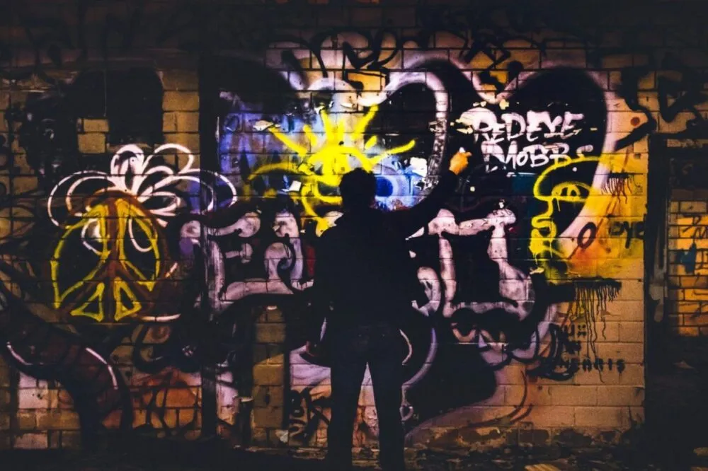 A man painting dark shade mural on wall