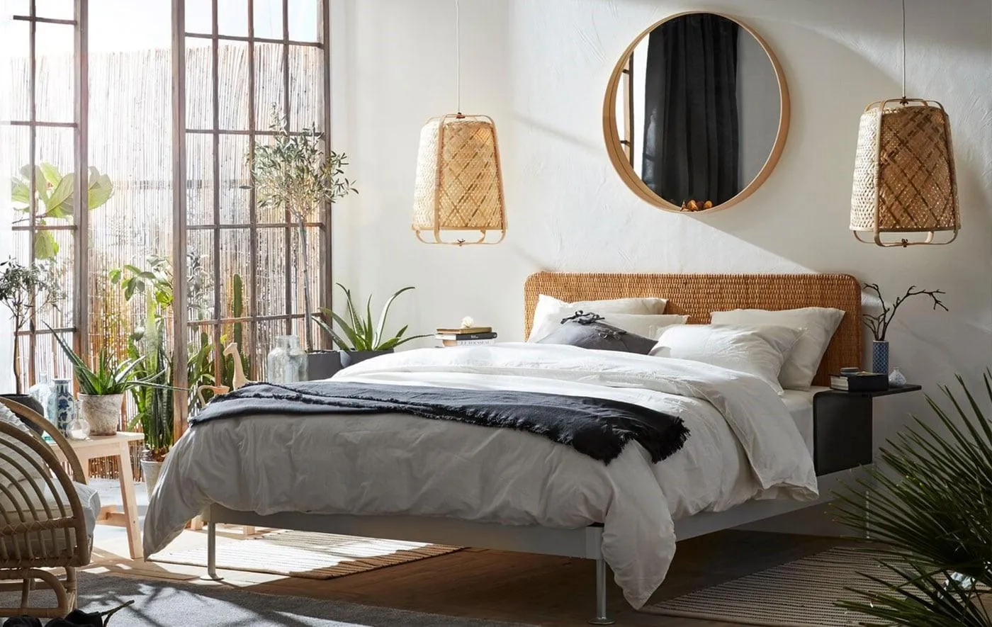 white bedroom with bed, round mirror, pendant light, indoor plants, and brown chair