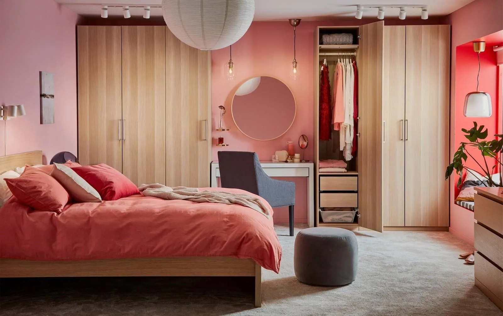 pink bedroom with bed, table, grey rug, white pendant light, round mirror, closet, table and chair