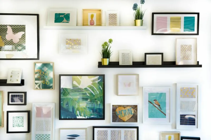 wall mounted showcase with paintings and photo frames on it