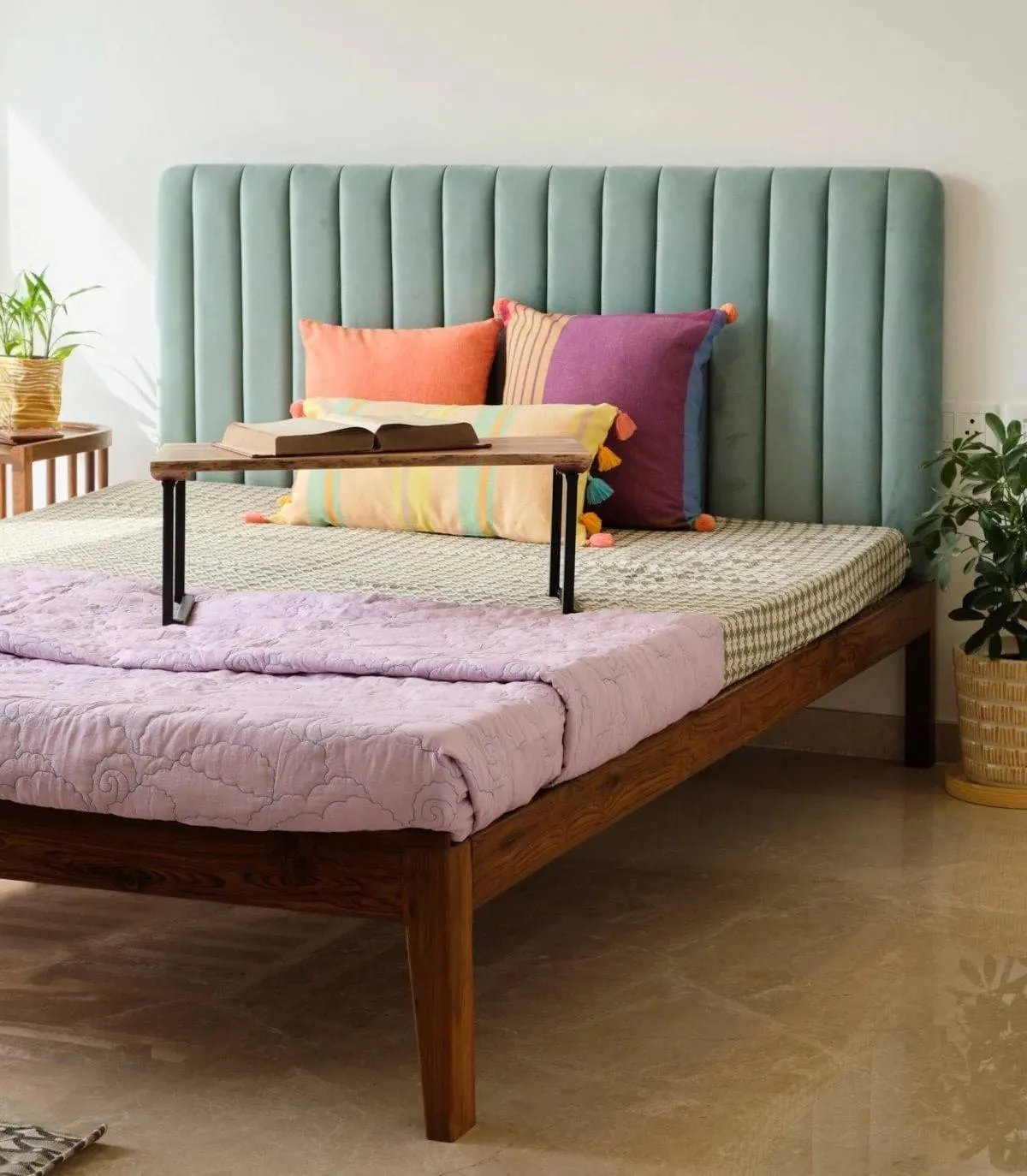 green bed in a bedroom with plants and a brown wooden floor