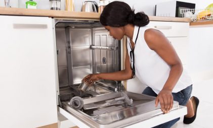 A girl using the dishwasher. how to clean the dishwasher with vinegar.