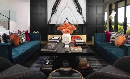 modern home decor idea for a dark themed living room with black accent wall, blue sofa, black centre table, colourful throw cushions