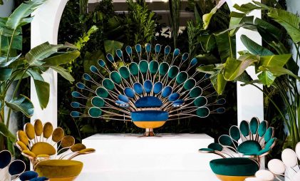 Beautiful blue peacock design sculptural furniture placed outside, surrounded by trees and plants.