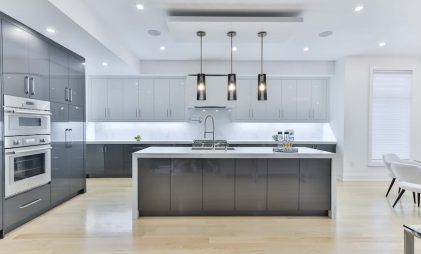 modern kitchen design in white and grey with a workstation sink in the middle and ceiling lights